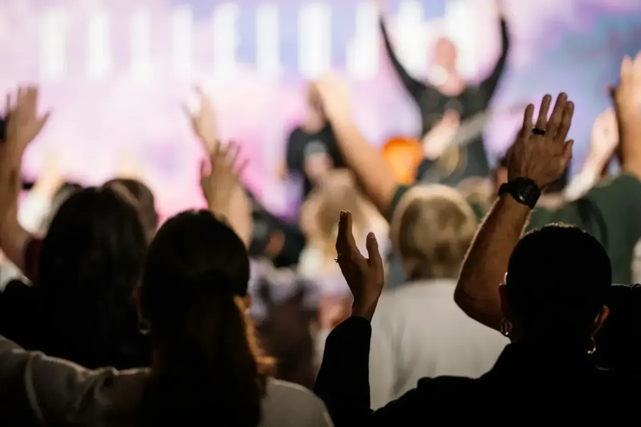 People lifting their hands in worship while the band plays